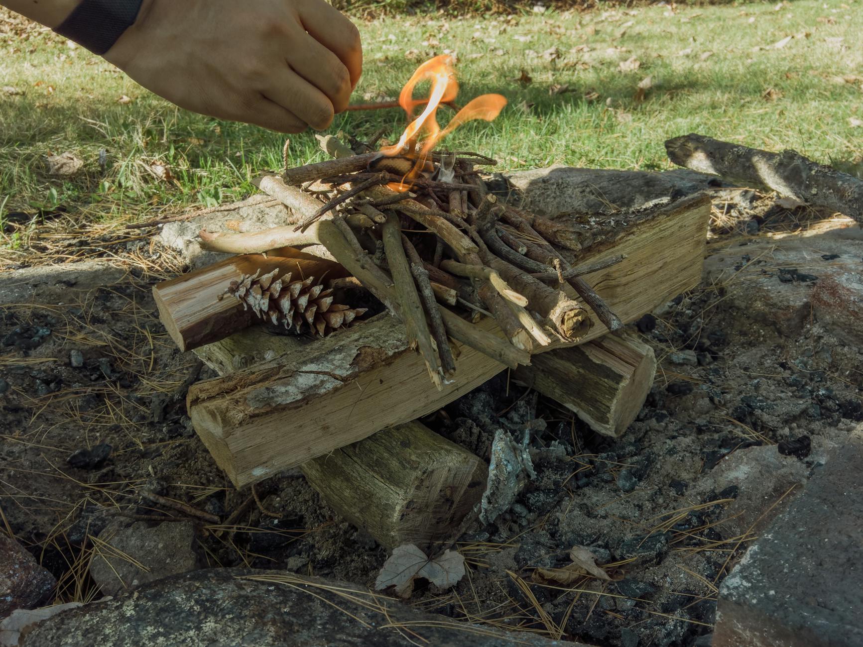 Rozpalanie ogniska na zewnątrz za pomocą patyków, polan i szyszki