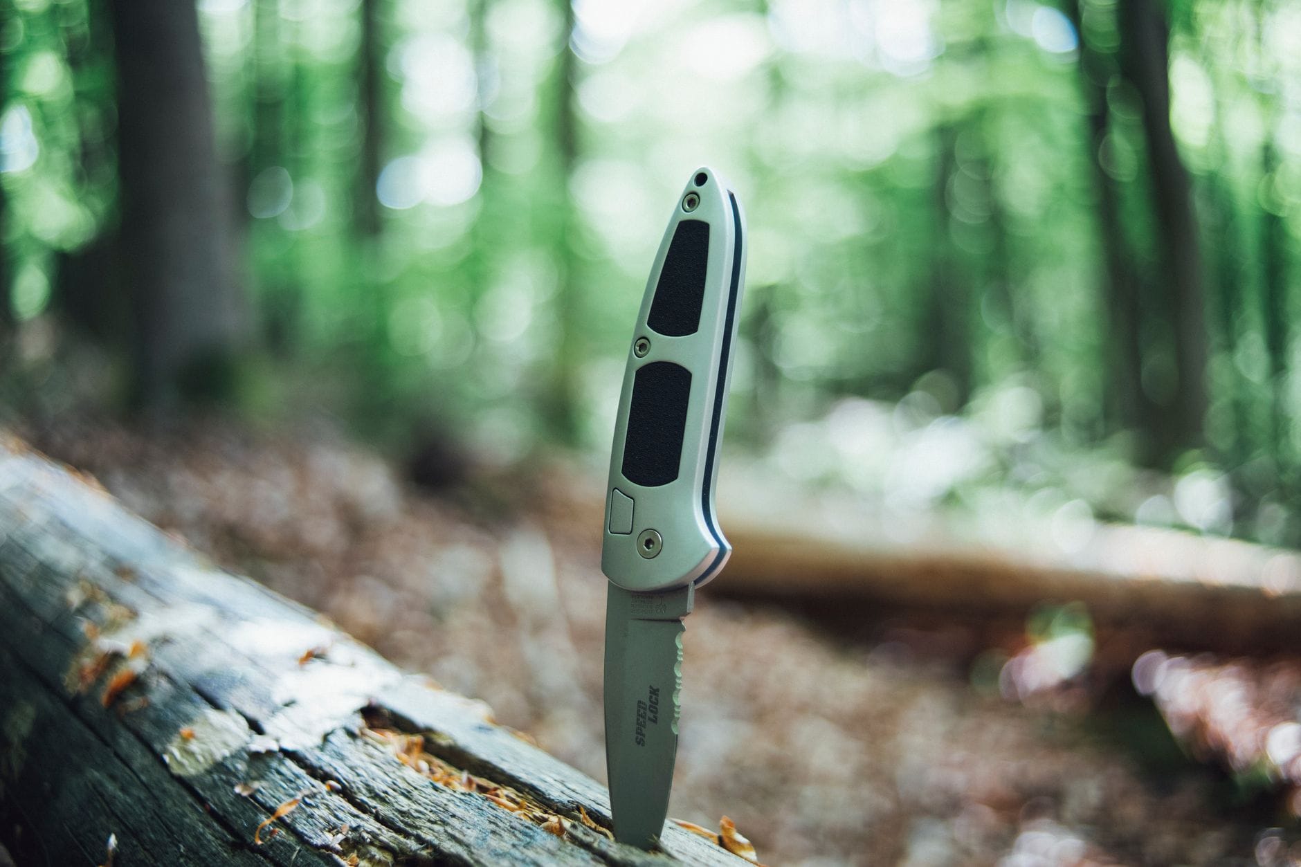 Składany nóż w lesie, zbliżenie narzędzia do bushcraftu i survivalu