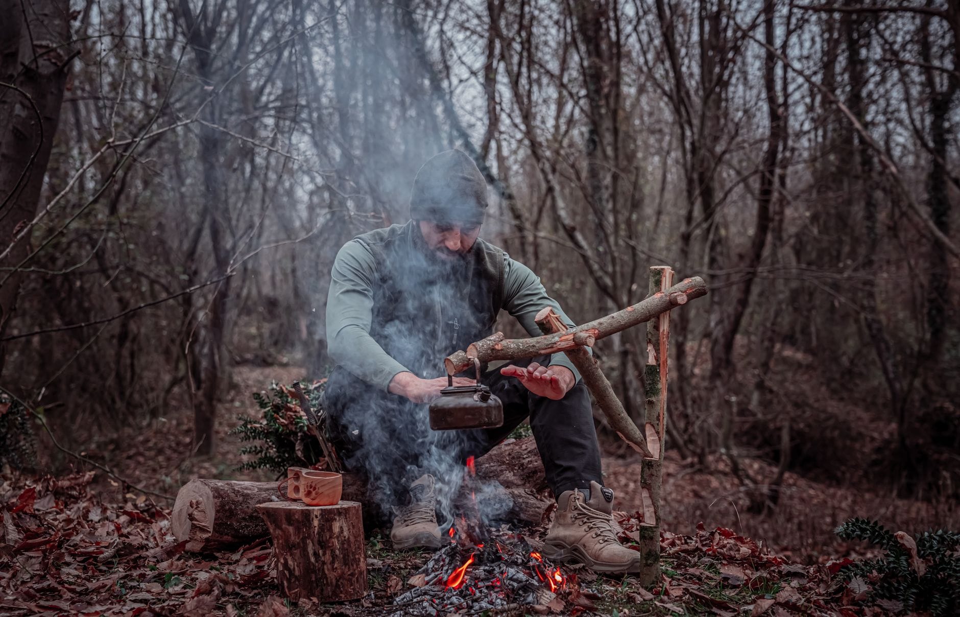 Bushcraft miejski wykorzystaj leśne umiejętności w codziennym życiu Mężczyzna gotuje nad ogniskiem w gęstym lesie, trening przetrwania